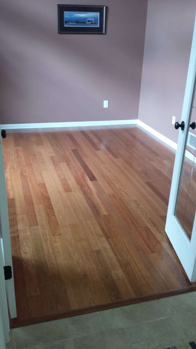 Golden oak strip hardwood flooring down a hallway with chair rail trim